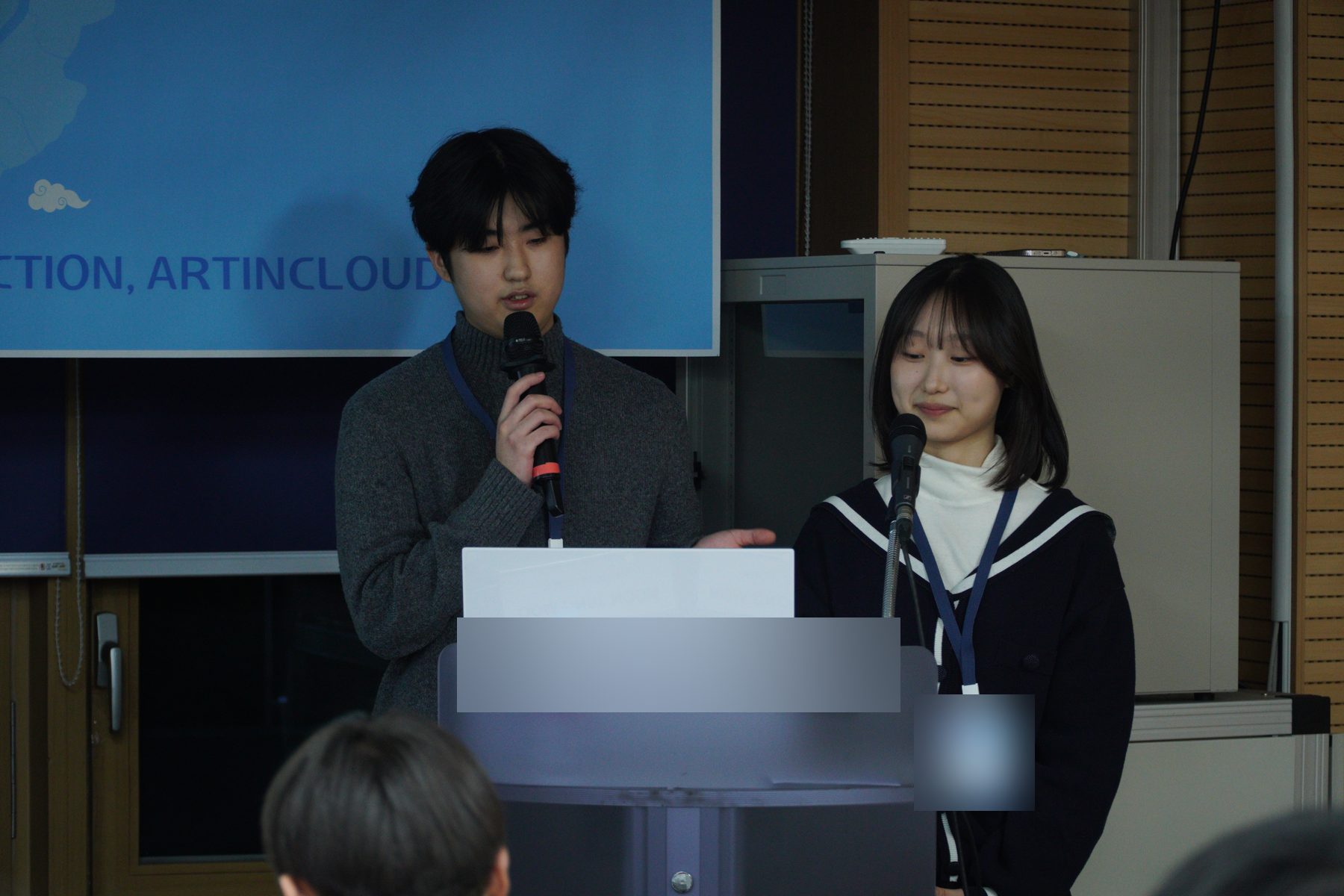 행사에서 마이크를 들고 발표하는 청년들